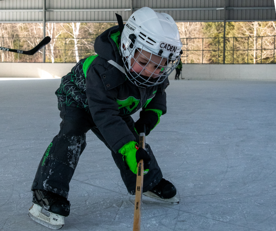 child skating with hockey stick and helmet