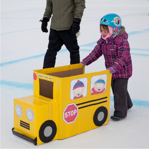 Child pushing a toboggan shaped like a yellow school bus.