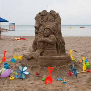 sand sculpture with colourful plastic shovels around it