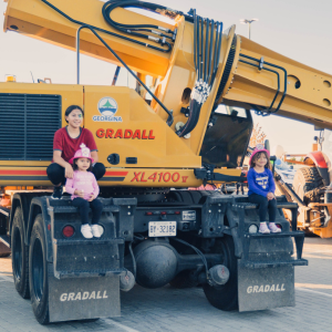 Yellow front loader with parent and 2 children sitting on the tracks