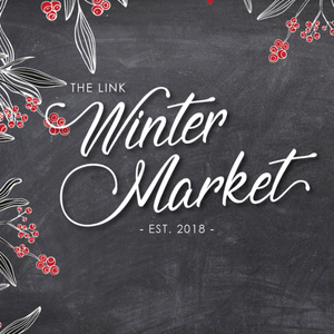 Illustrated logo for The Link Winter Market, established 2018, featuring holly berries and the event name on a grey chalkboard-style background.