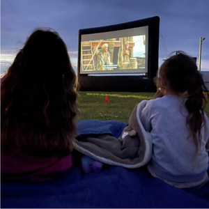 two people watching a movie on an inflatable screen outside at night