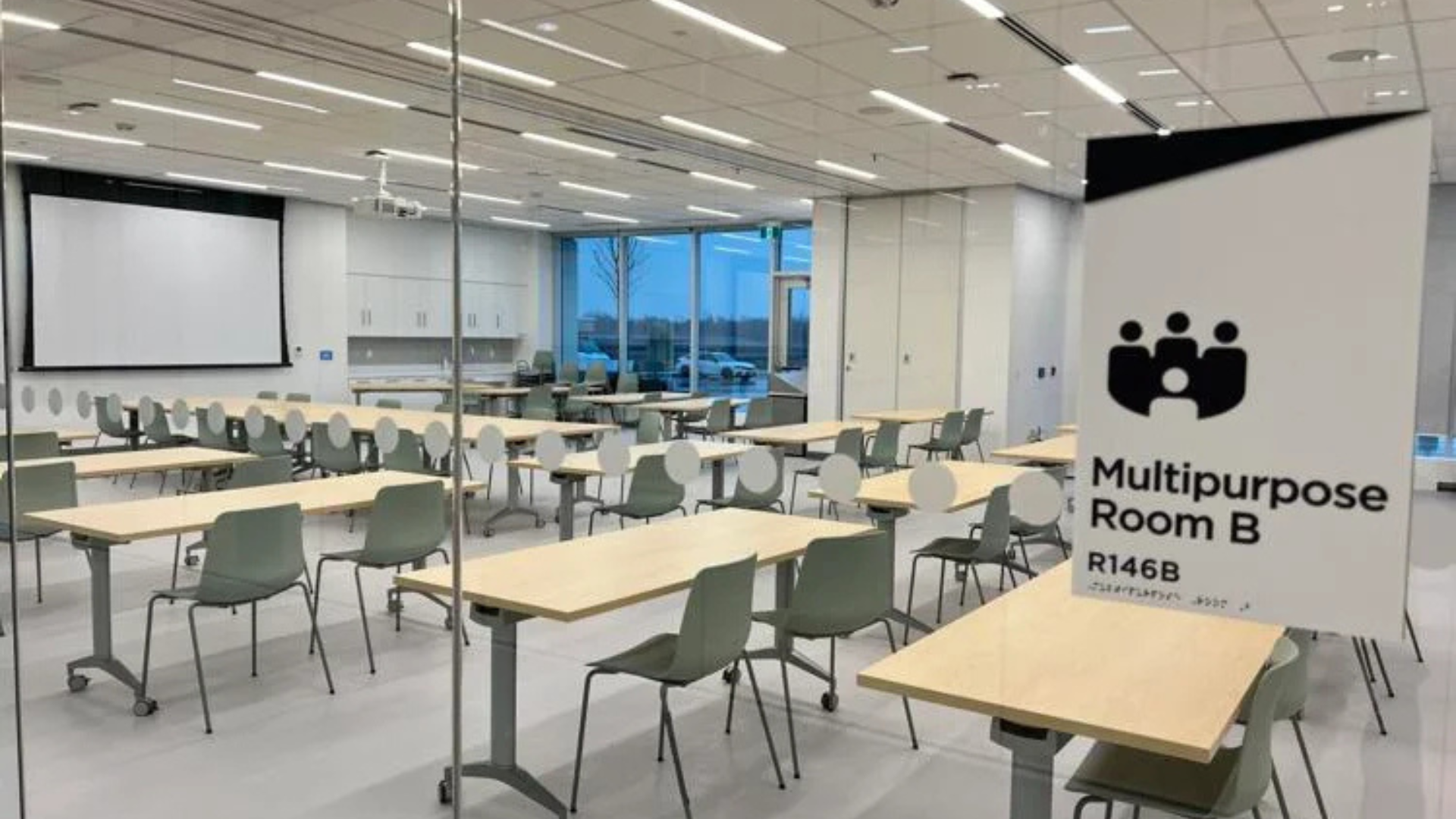 Empty program room with tables and chairs set up facing a screen on the wall