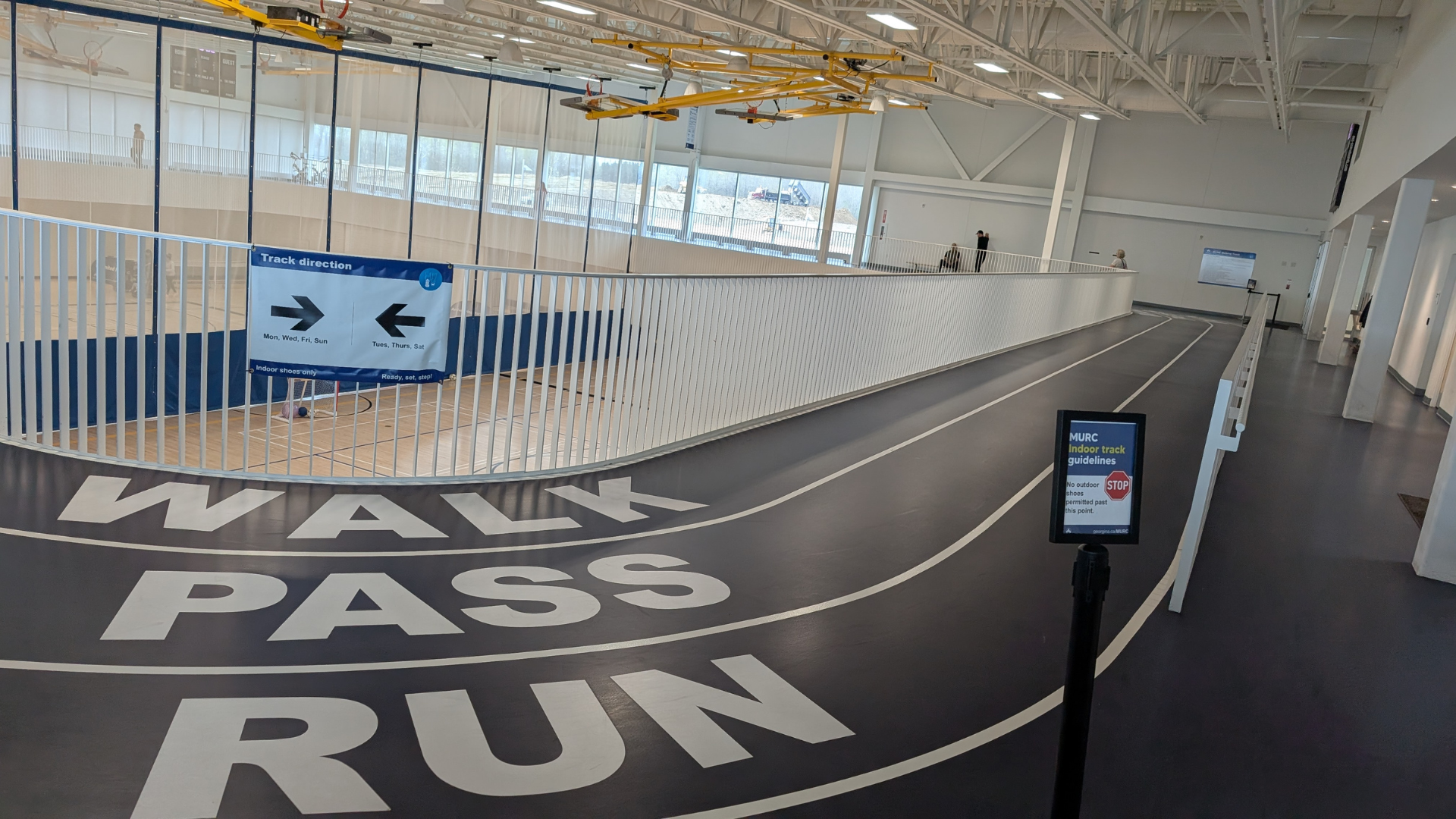 Walking track above a gymnasium with Walk Pass and Run on the ground and a small sign on a stand
