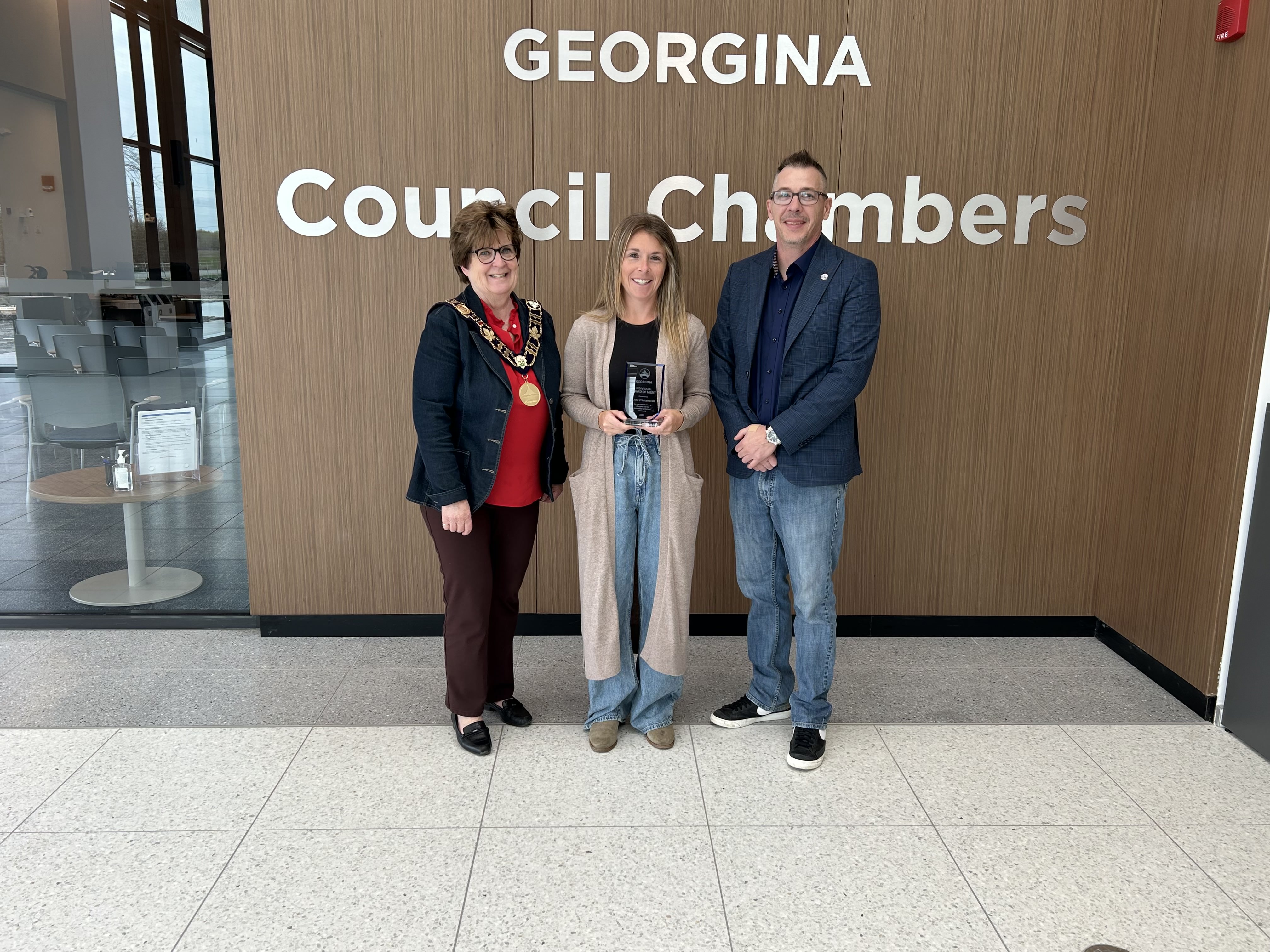 Mayor, councillor and recipient standing in front of the Council Chambers