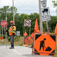Person with stop sign and road work construction signs