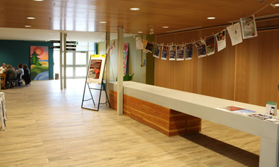 Main hallway of the Link with wood floors and a long desk with a white counter, people at a table in the far background