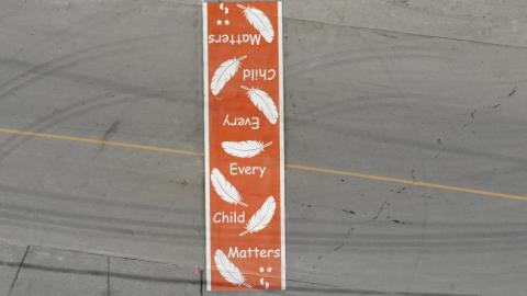 Orange crosswalk says every child matters with feathers, handprints and footprints
