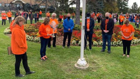people in orange shirts around flag pole at civic centre Group of people in orange shirts surrounding a flagpole