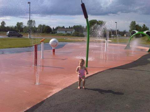 Splash pad area with water fixtures and a small child