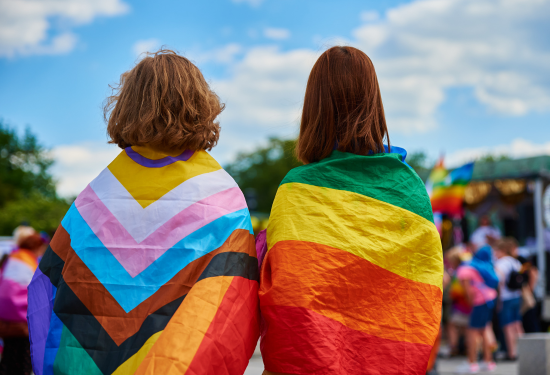 two children wearing pride flags around their shoulders