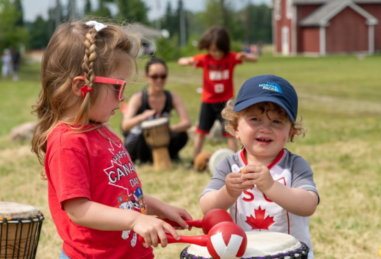 two children with a drum wearing red maple leafs
