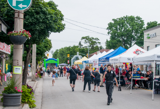 people walking on a street with tents at a festival