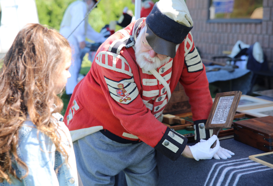 man in historical military dress showing something to a young girl
