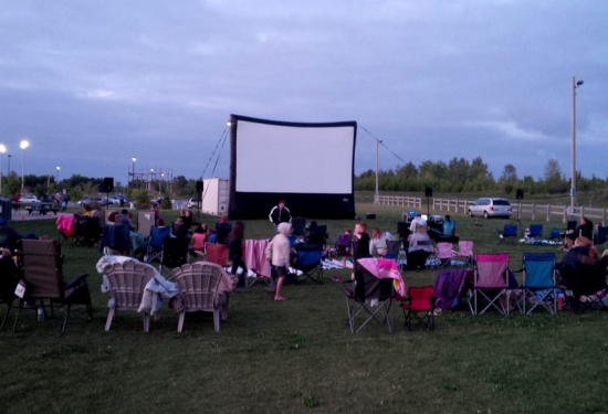 inflatable movie screen in a park with people sitting in lawn chairs