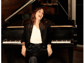 lady sitting on piano bench in front of a piano
