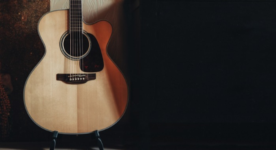 Close-up of a classical wooden guitar on a dimly lit stage.