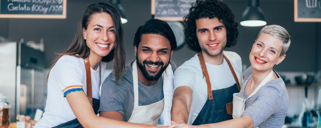 four people standing side by side with their hands on top of each other