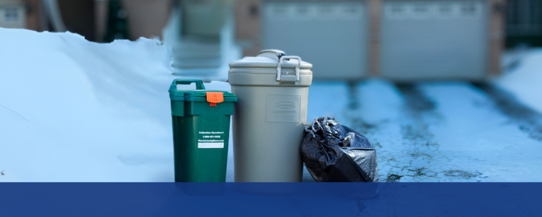 green bin, garbage can and garbage bag at the end of a snow-covered driveway